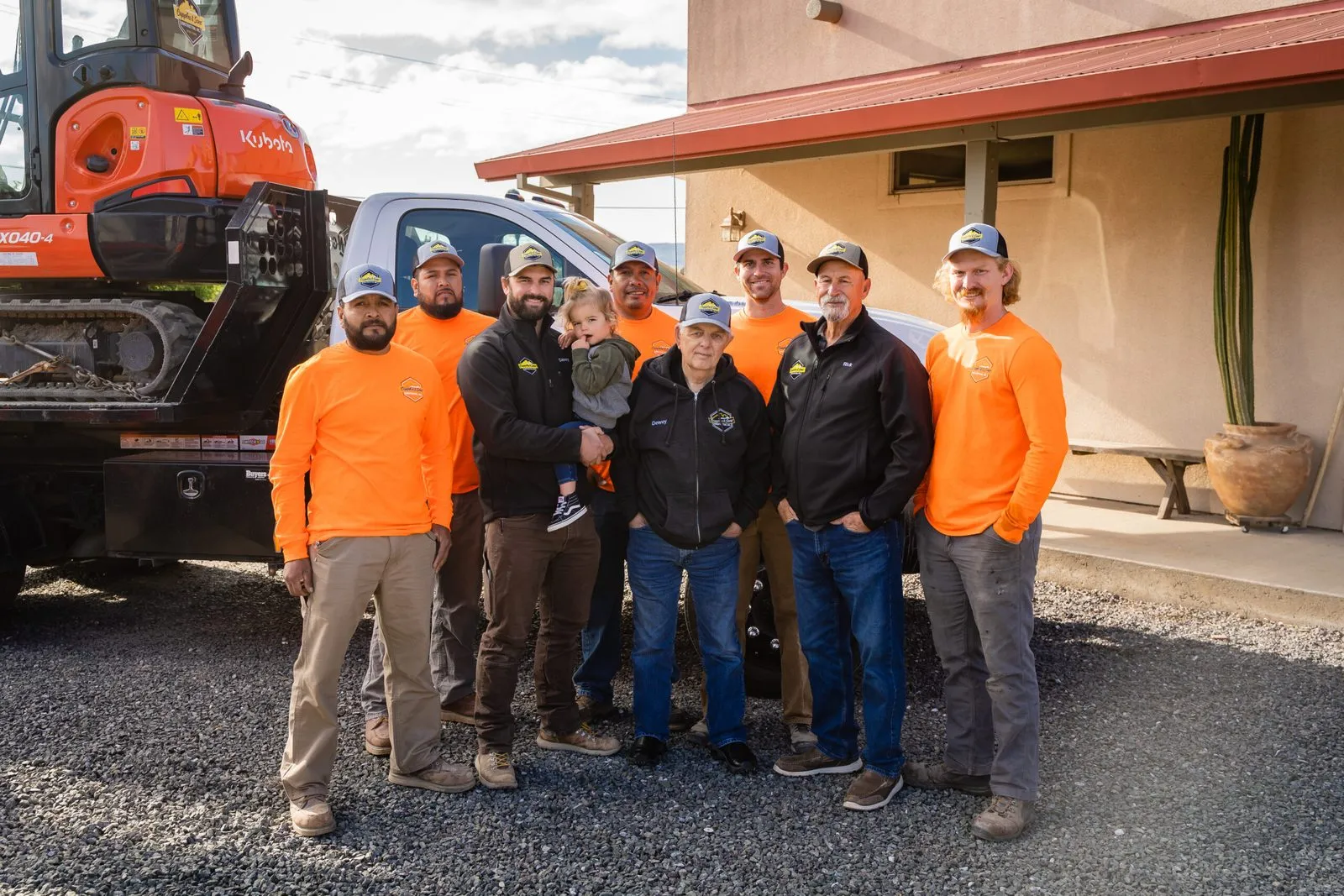 The Cupples and Sons crew together on a job site in front of an excavator